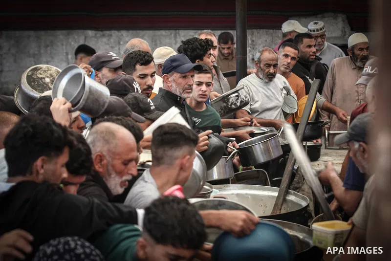 Displaced Palestinians gather to receive free meals at a food distribution point in the Nuseirat refugee camp, central Gaza Strip, on October 22, 2026, amid worsening food insecurity caused by the war. On October 19, the...
