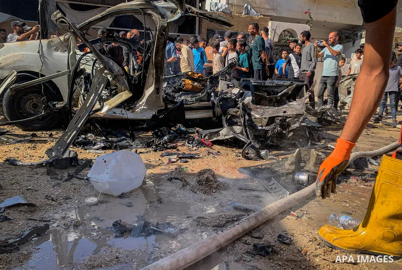 Palestinians gather at the site of an Israeli airstrike targeting a vehicle in the Tel al-Hawa neighborhood, southwest of Gaza City, on October 22, 2026, as Civil Defense crews try to extinguish flames in the wreckage. T...