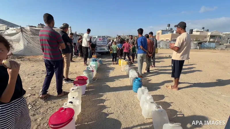 Displaced Palestinians, including children, gather to collect water amid ongoing water supply shortages and damaged infrastructure caused by the war and continued displacement.
