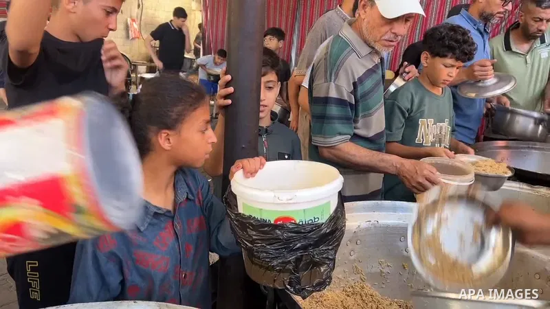 Restrictions Summary: APA wire clients only Shortlist: APAwire - APA wire clients only, Nuseirat- June 13, 2026. Displaced Palestinians, including women and children, gather to receive hot meals distributed by a charity...