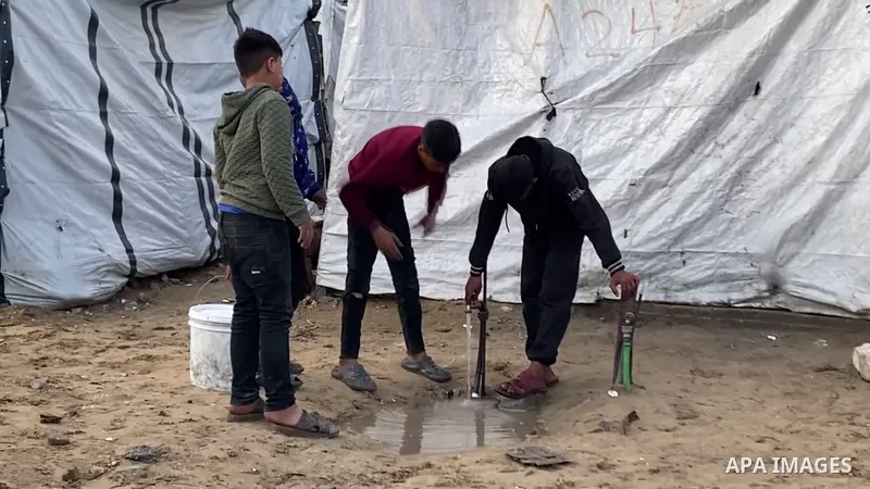 Restrictions Summary: APA wire clients only Shortlist: APAwire - APA wire clients only, Gaza City- March 26, 2026. A displaced Palestinian woman, Mai Hassouna, sits with her children inside a tent flooded by rainwater fr...