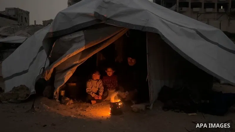 Restrictions Summary: APA wire clients only Shortlist: APAwire - APA wire clients only, Gaza- February 13, 2026. A Palestinian father lights a fire near his dilapidated tent to warm his children amid the cold weather and...